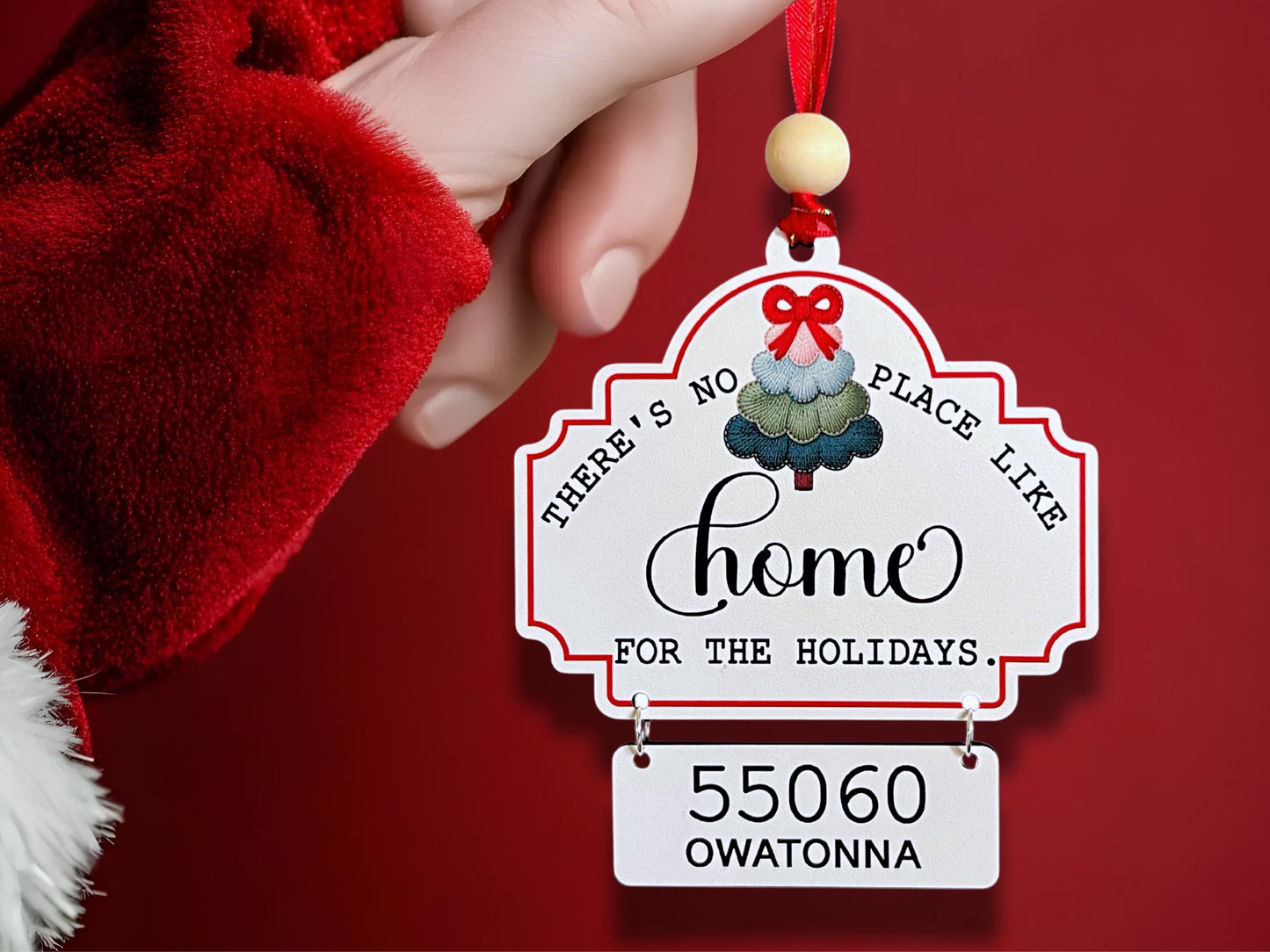 Decorative Christmas ornament with text and a tree design on a red background.