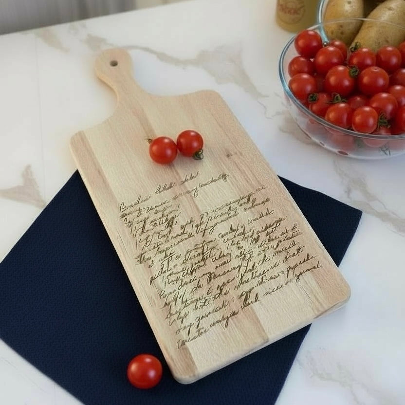 Wooden cutting board with engraved text and tomatoes on a marble surface