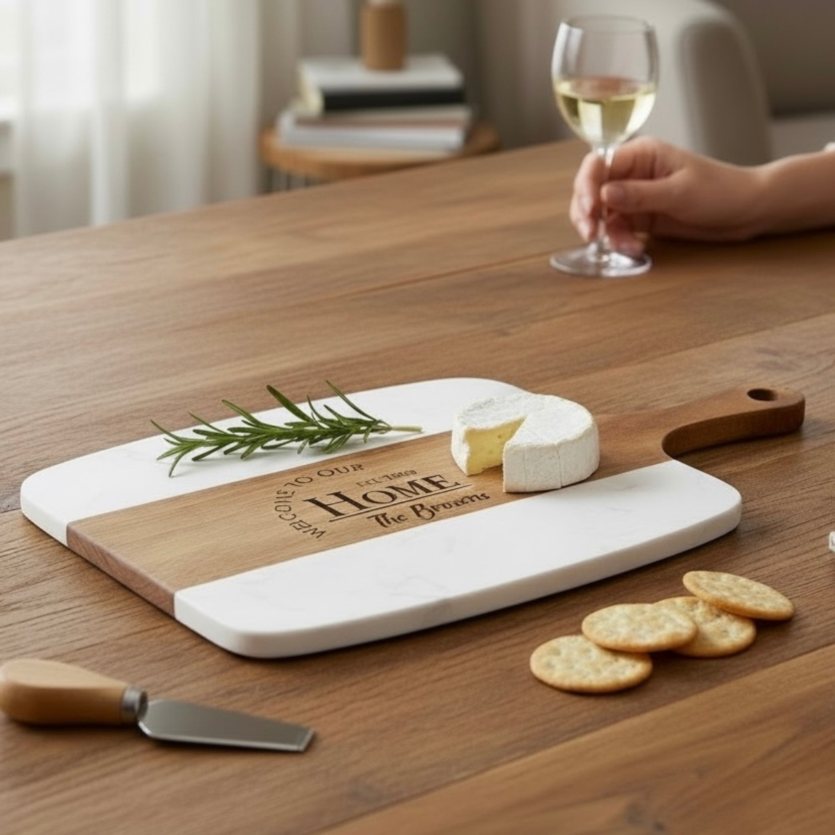 Personalized cheese board set on a wooden table with a glass of wine and crackers.