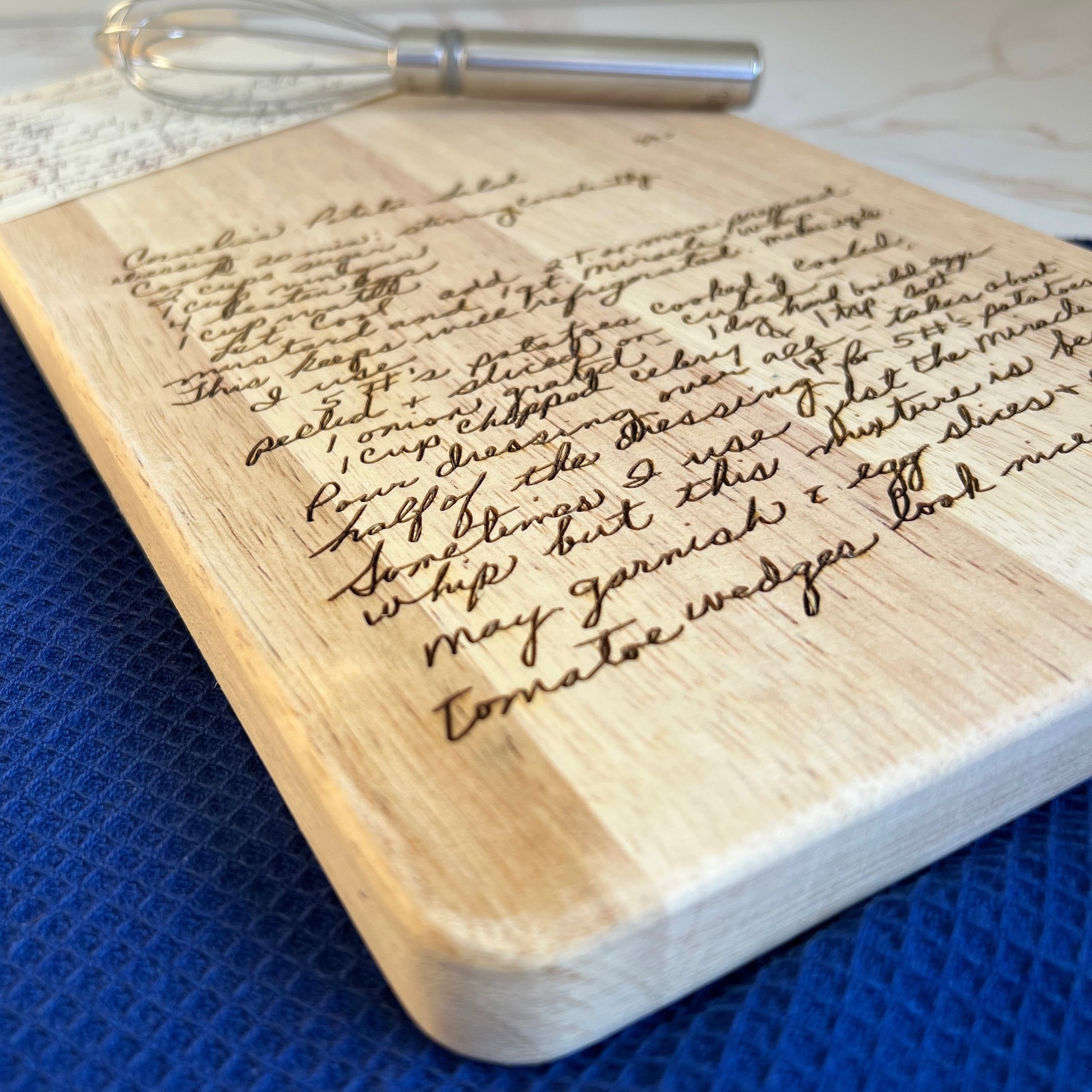 Wooden board with handwritten text and a whisk on a blue surface