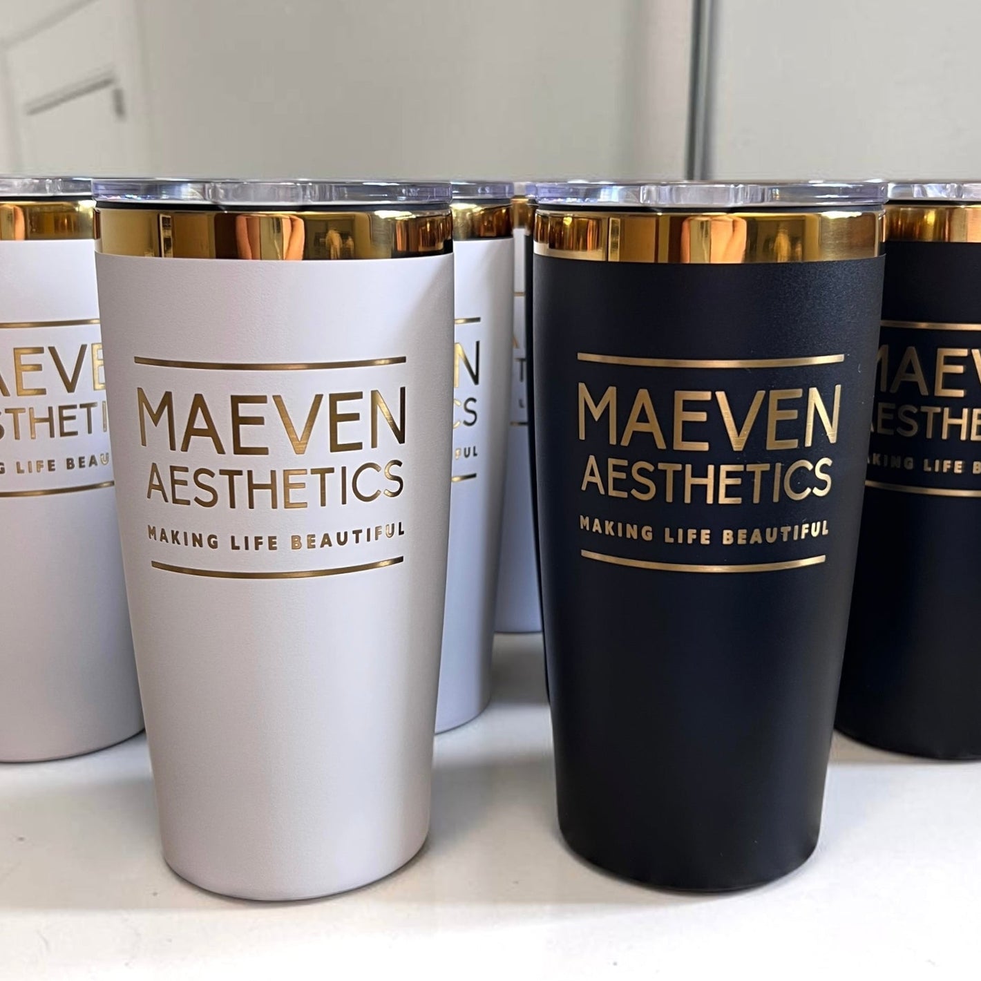 Set of tumblers with 'MAEVEN AESTHETICS' branding on a surface.