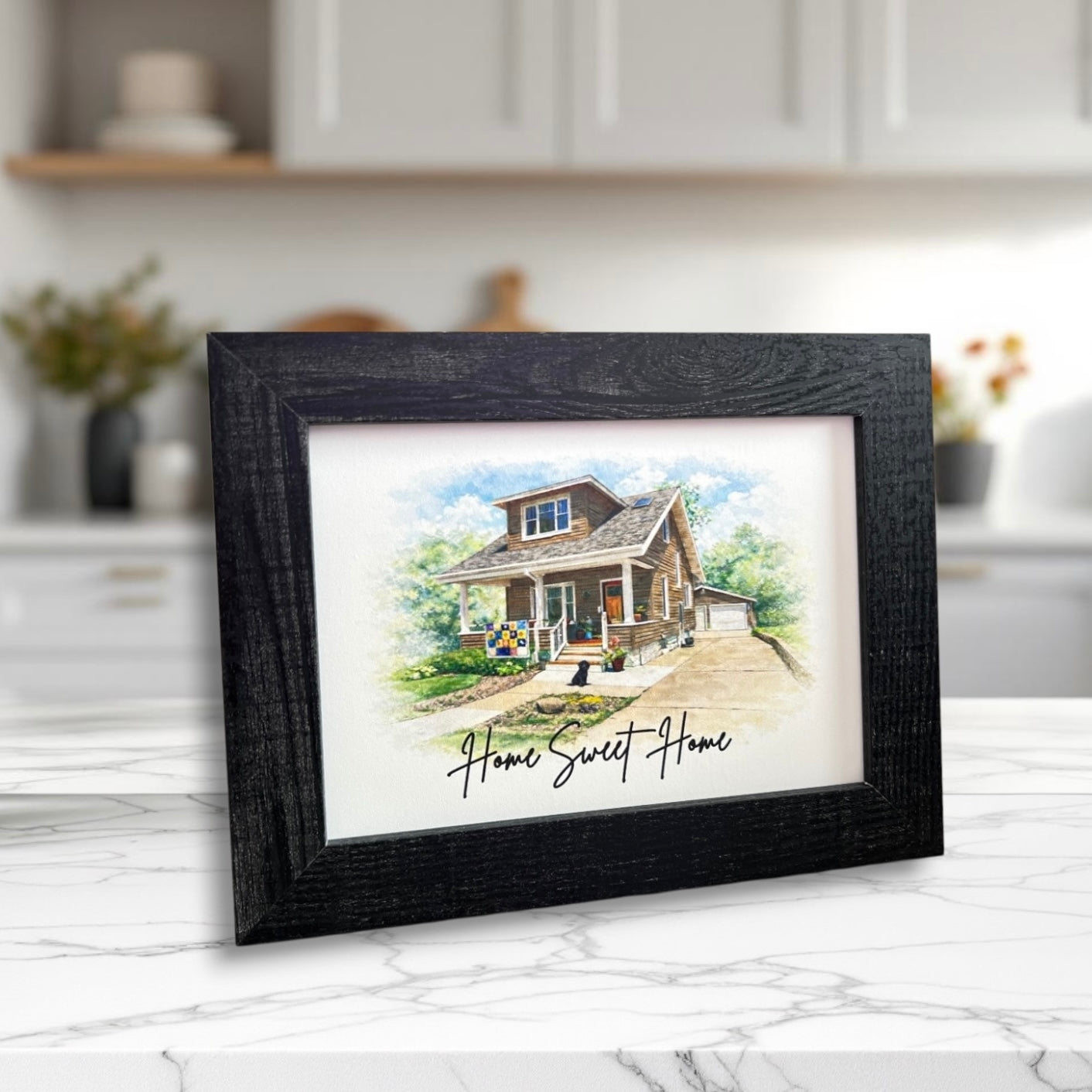 Framed artwork of a house with 'Home Sweet Home' text on a kitchen counter.