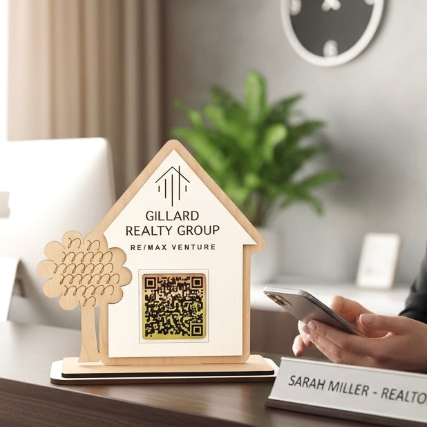 Wooden house-shaped sign with QR code for Gillard Realty Group in an office setting.